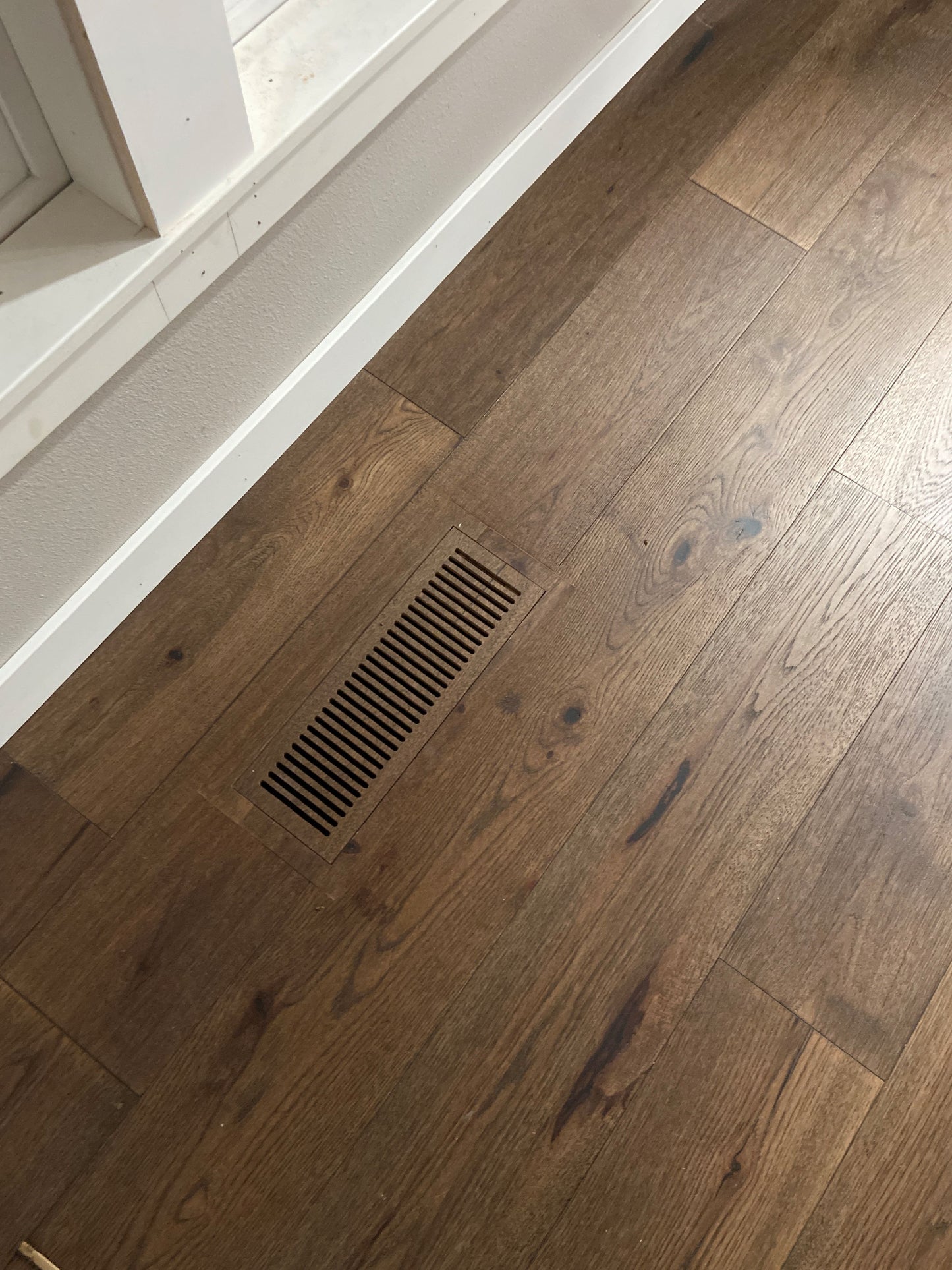 Close-up of LVP floor vent installed in a hallway, showcasing the smooth integration with luxury vinyl plank flooring for a seamless look.