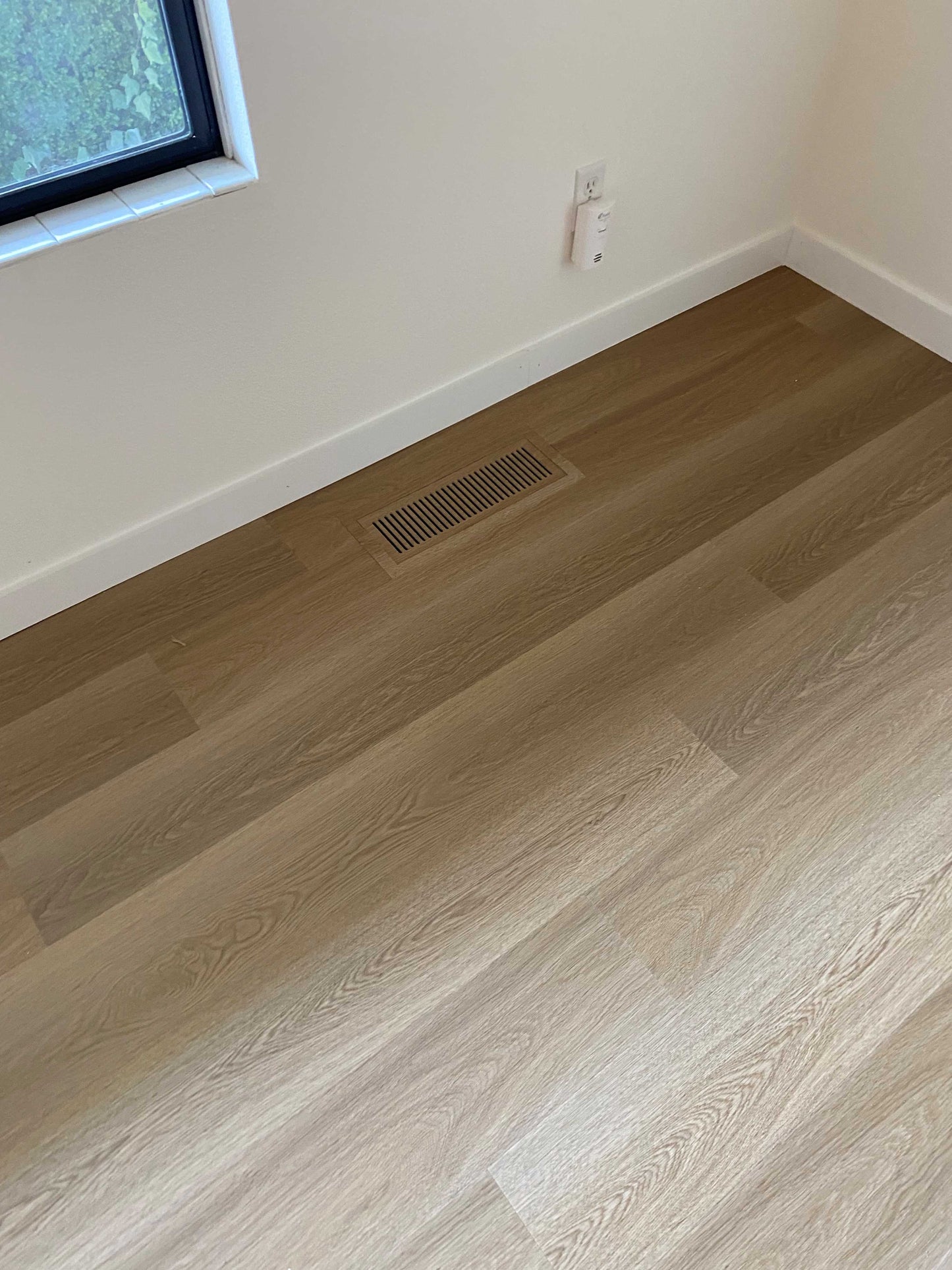 High-quality LVP floor vent installed in a living room, seamlessly matching the luxury vinyl plank flooring for a cohesive design.