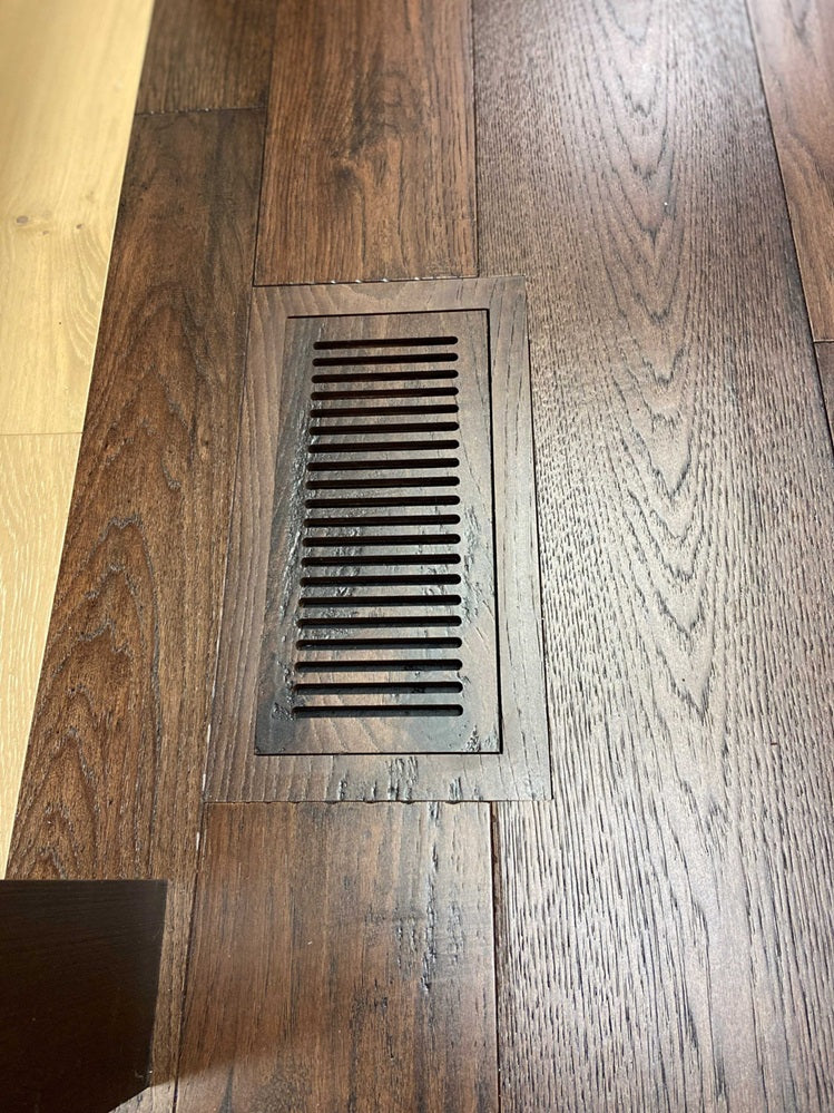 Close-up of LVP floor vent installed in a hallway, showcasing the smooth integration with luxury vinyl plank flooring for a seamless look.