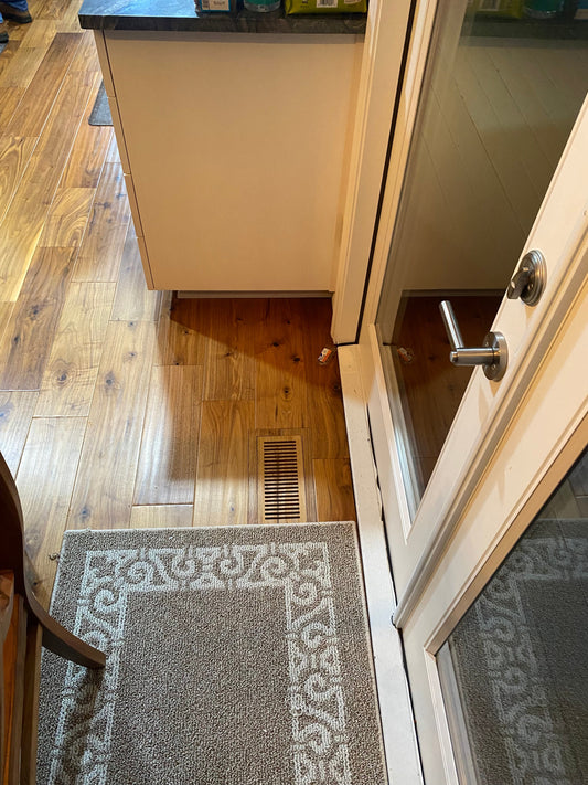 Floor-matched vent in an entryway near a kitchen