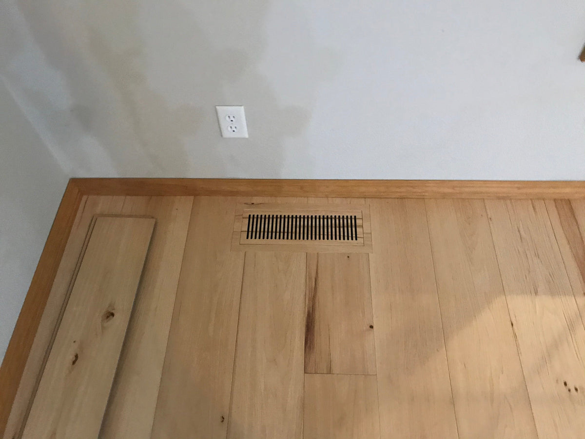 Flush floor vent made from a light wood-look COREtec plank, with a spare plank beside it