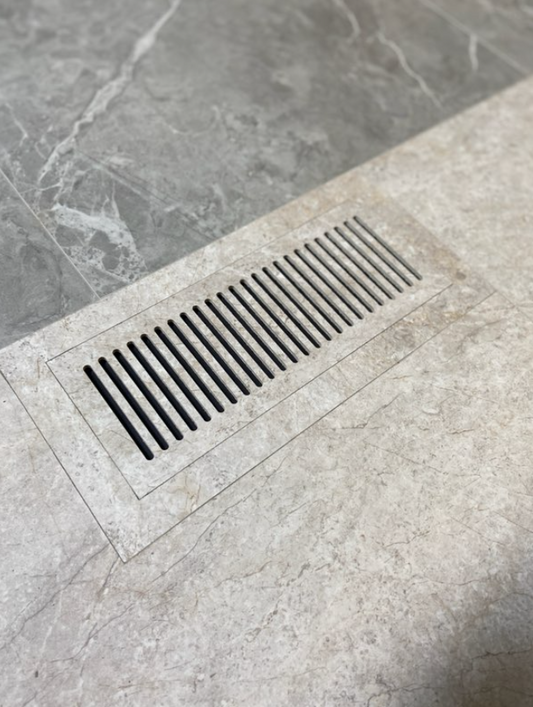 Flush floor vent in a gray luxury vinyl tile floor